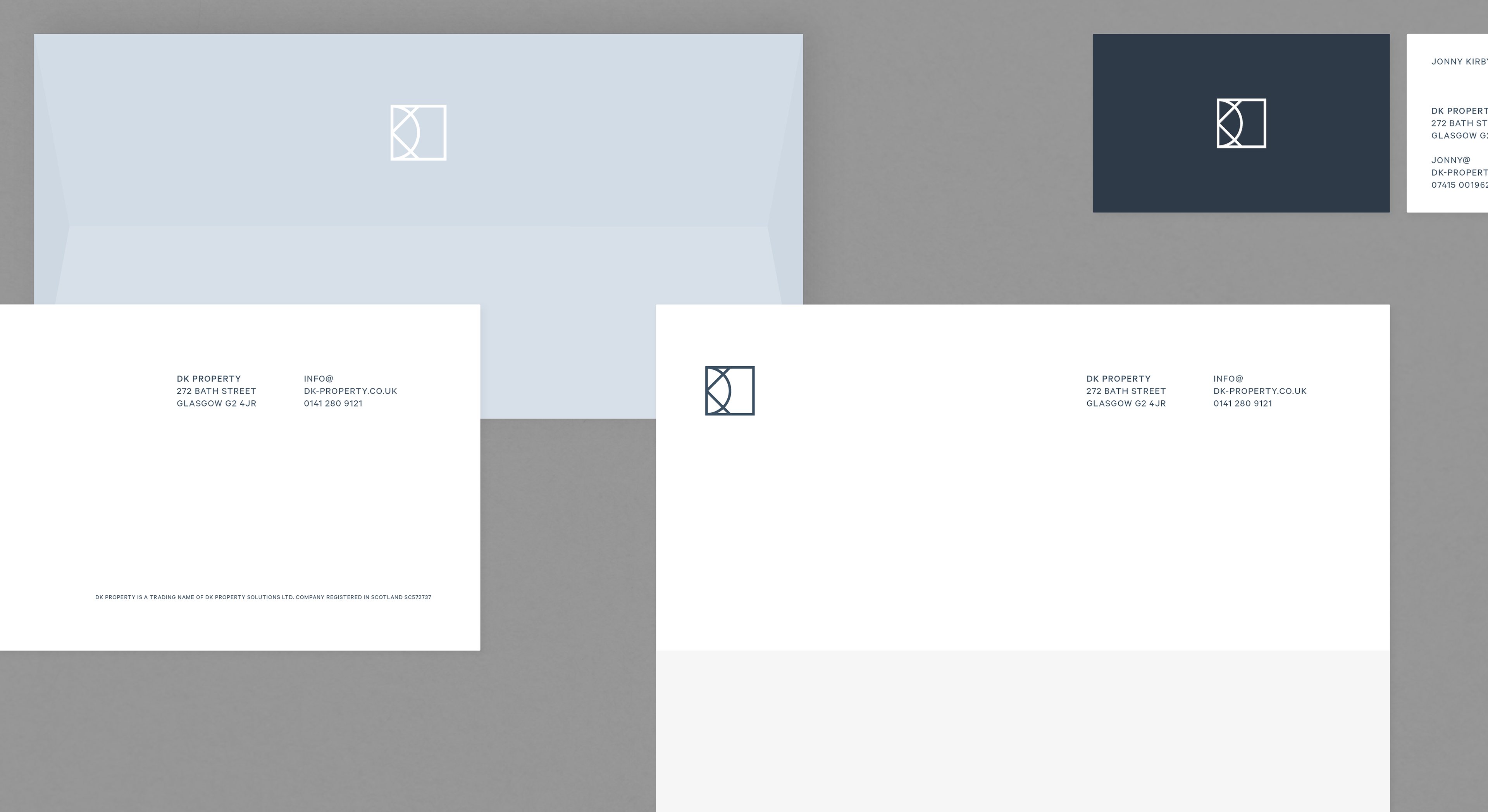 Envelopes, letterhead and business cards carrying the DK monogram in navy on white and pale blue.