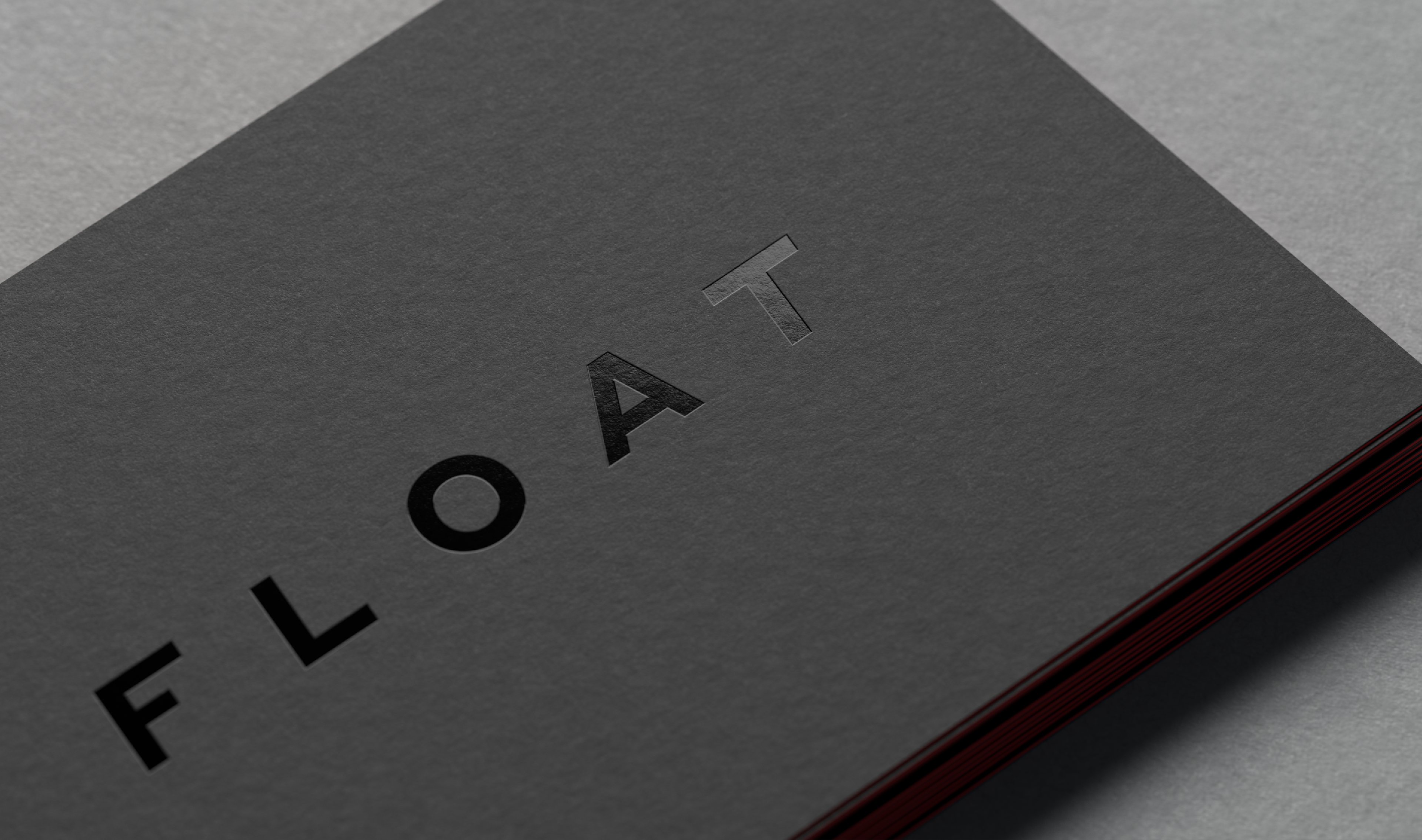Close-up of a black business card with the Float logotype in glossy black-on-black foil.